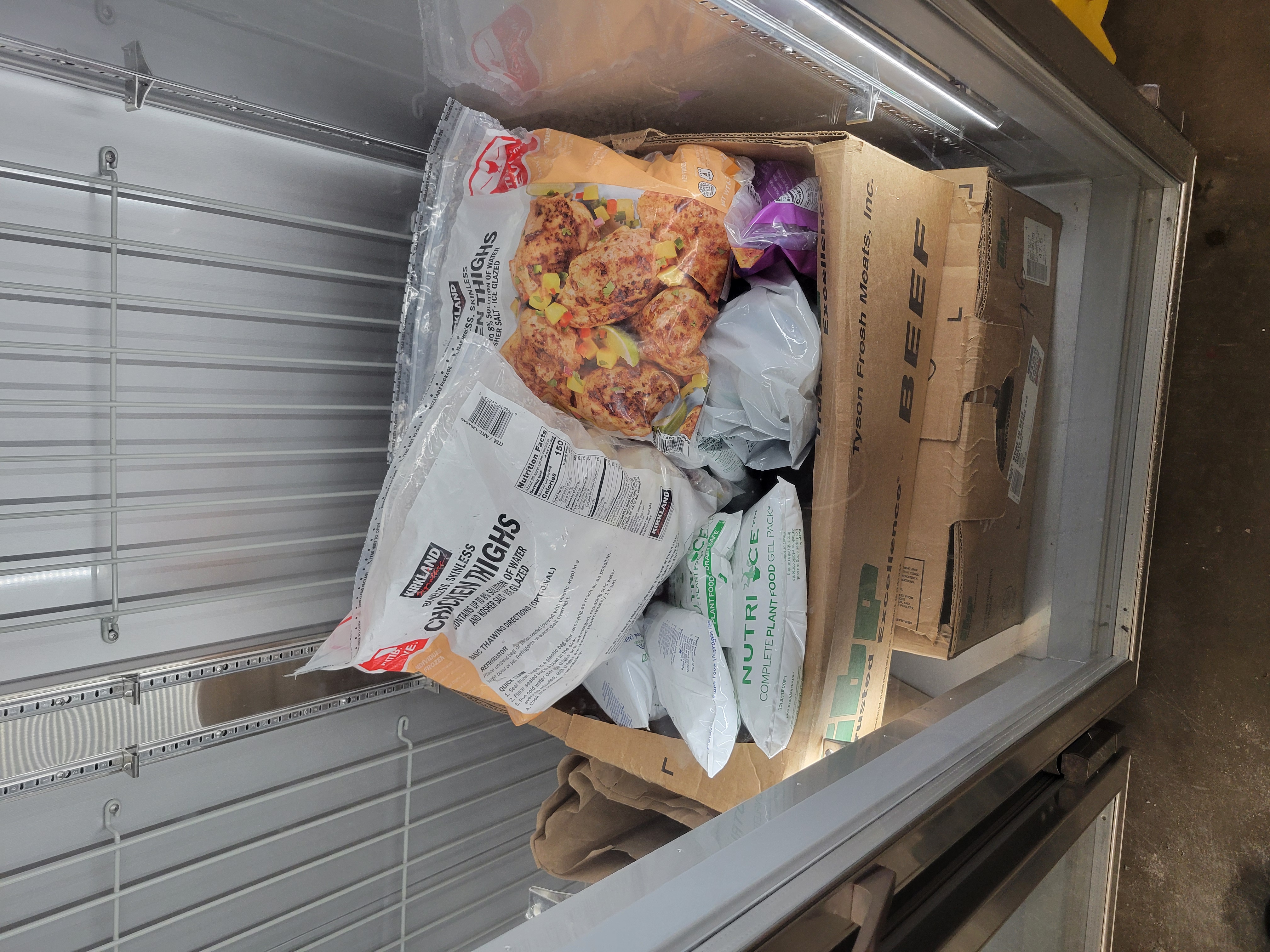 Bags of chicken thighs on top of food gel packs in a box that is in a fridge.